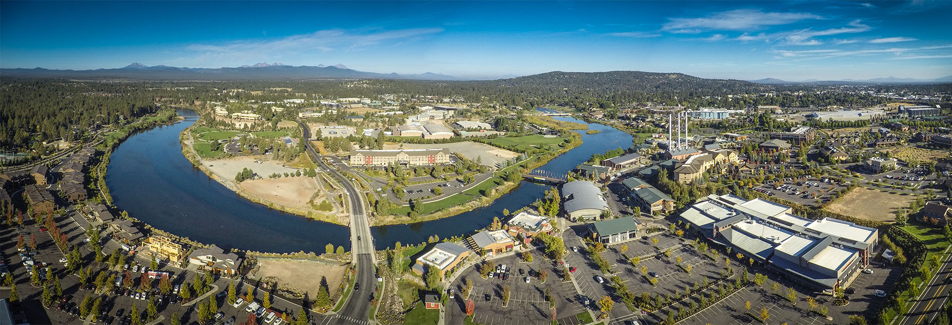 Aerial view of the Deschutes River bend near the Old Mill with the Cascades in the background.