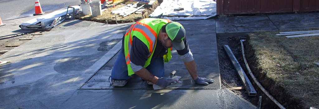 Construction worker smoothing fresh concrete for a new sidewalk