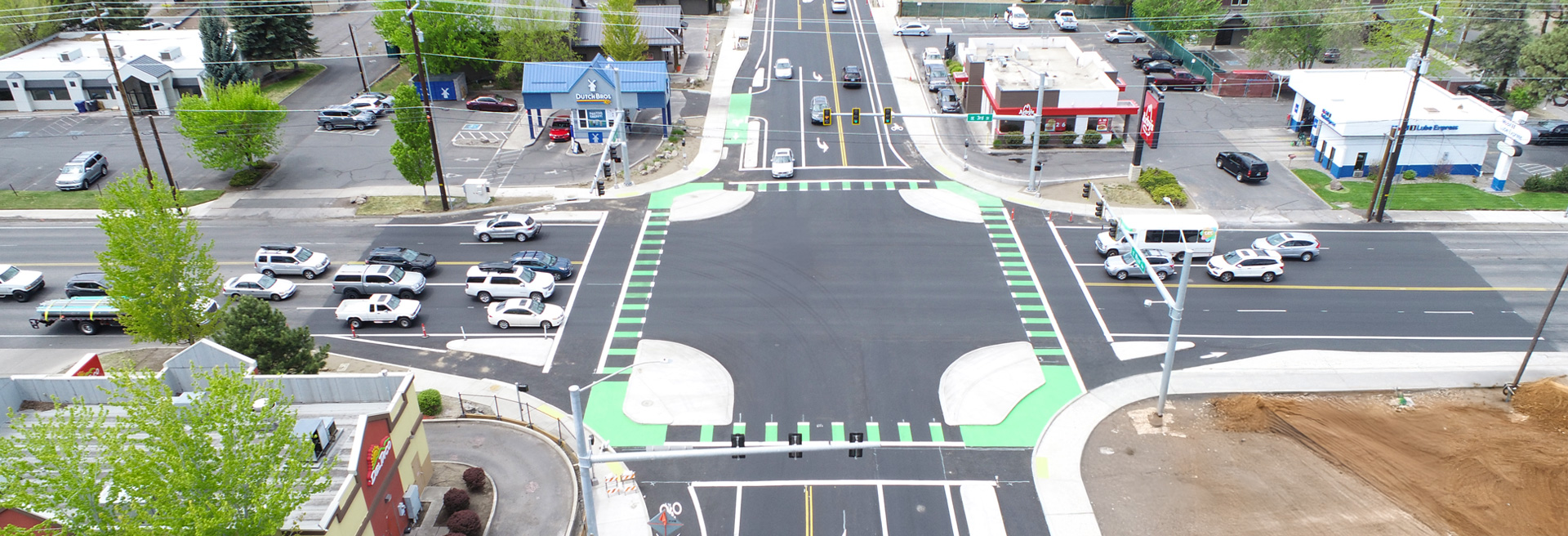 Protected intersection with stop lights and green areas for bicycle riders. Cars are stopped at the stoplight. View is looking West on Wilson Ave.