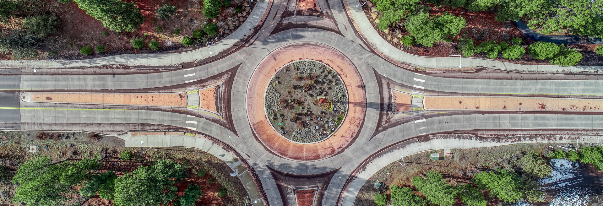 Overhead view of a roundabout traffic circle. Trees surround the circle.